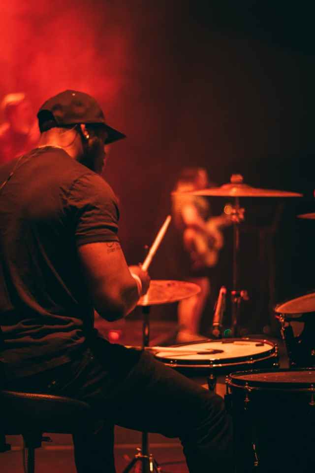 man s wearing black shirt playing drum